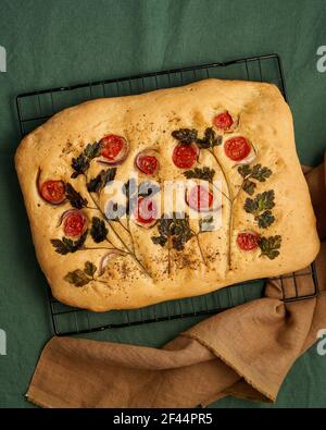Focaccia, Fladenbrot mit Tomaten, auf dunkelgrünem Leinentischtuch. Draufsicht Stockfoto