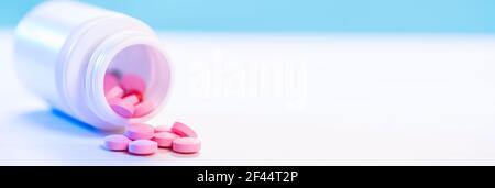 Rosa Pillen werden aus einer Plastikflasche Medizin auf einen weißen Tisch gegossen. Pharmaindustrie. Gesundheitswesen und Medizin. Pharmakonzept. Stockfoto