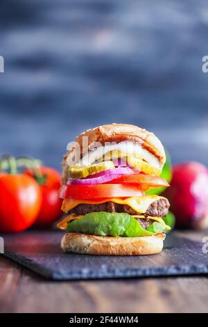 Ein großer, fetter, saftiger Doppel-Cheeseburger aus zwei 100% Rinderpasteten, geschmolzenen Käsescheiben, Zwiebeln, Gurken, Salat, Tomaten, Und Mayo. Stockfoto