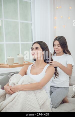 Teenage-Mädchen Flechten Haare zu jungen lächelnden Frau Stockfoto