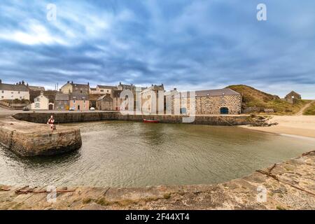 PORTSOY ALTER HAFEN MORAY FIRTH ABERDEENSHIRE SCHOTTLAND BLICK ÜBER DIE HAFEN ZU DEN STEINHÄUSERN UND EIN ROTES BOOT Stockfoto