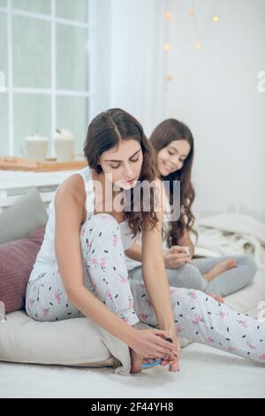 Frau malen Zehennägel Mädchen sitzen hinter Stockfoto