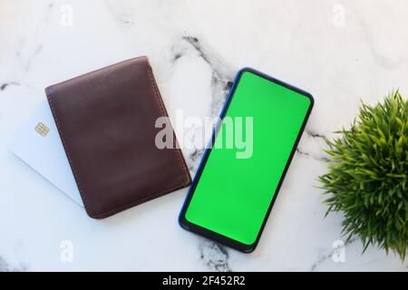 Ansicht von oben auf Smartphone mit leerem Bildschirm, Brieftasche und Karten auf dem Tisch Stockfoto