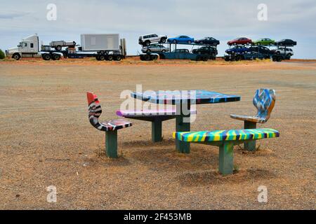 Australien, farbenfrohe Sitzgruppe im Ruhebereich und Lastwagen mit Anhängern und Autos auf dem Stuart Highway Stockfoto