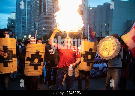 La Paz, Bolivien. März 2021, 18th. Eine Gruppe von Männern mit hausgemachten Schilden beobachten bei einer politischen Kundgebung, wie ein Feuerverschnaufer Feuer spuckt. Tausende regierungsnahe Demonstranten fordern die Verurteilung der ehemaligen Interimspräsidentin Jeanine Anez und ihrer Minister. Die Politiker wurden wegen Terrorismus, Aufruhr und Verschwörung verhaftet und stehen bei einer Verurteilung bis zu 30 Jahren Gefängnis gegenüber. Quelle: Radoslaw Czajkowski/dpa/Alamy Live News Stockfoto