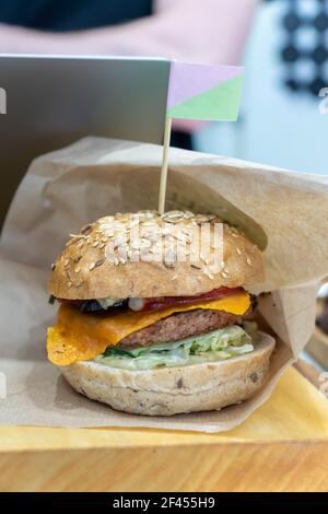 Veganer hausgemachter Bohnenburger mit pflanzenbasiertem Burger-Patty, Sojakäse und Soße auf Holztisch. Stockfoto