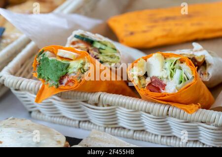 Sandwich in flachem Orangenbrot gerollt. Veganes Sandwich in Lavasch mit Gemüse auf dem Street Food Markt. Stockfoto