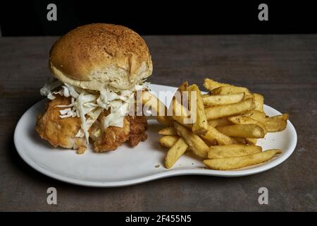 Eine Nahaufnahme von einem leckeren knusprigen Hähnchenburger mit gehackten Kohl und pommes auf einem Teller Stockfoto