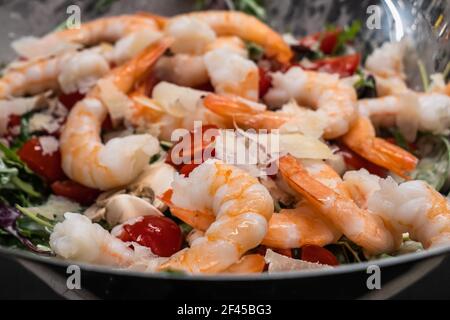 Rucola oder Rocket Salat mit Garnelen oder Shrimps, Tomaten, Parmesankäse und Champignons, serviert in einer Silberschale Stockfoto