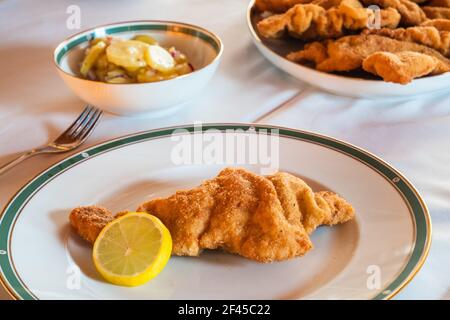 Leckeres Wiener Schnitzel oder Wiener Schnitzel mit Zitronenrad und einer Seite Kartoffel Salat, traditionelle österreichische Küche Stockfoto