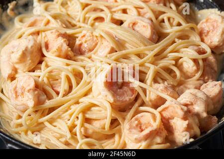 Pasta mit Garnelen-Sahne-Sauce in der Pfanne, Spaghetti mit Meeresfrüchten, reichhaltige Sahne auf Kochtopf Stockfoto