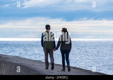 Lyme Regis, Dorset, Großbritannien. 19th. März 2021. UK Wetter: Sonnenschein und Wolken zusammen mit einer kühlen Brise im Badeort Lyme Regis. Die Leute machen einen flotten Spaziergang entlang der Cobb, aber eine erfrischende Meeresbrise hielt viele Menschen fern. Kredit: Celia McMahon/Alamy Live Nachrichten. Stockfoto