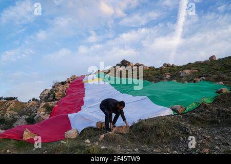 Akre, Irak. März 2021, 18th. Kurden setzen in der Altstadt von Akre eine Flagge Kurdistans über einen der Berge.die Stadt Akre im Gouvernement Duhok bereitet sich darauf vor, Nowruz (das persische Neujahr oder das kurdische Neujahr) zu feiern, indem sie Fahnen über den Bergen aufhängen. Das persische Neujahr oder das Kurdische Neujahr ist eine alte zoroastrische Tradition, die von Iranern und Kurden am 20th. März jedes Jahres gefeiert wird und mit der Frühlingstaquinoktikum zusammenfällt. (Foto: Ismael Adnan/SOPA Images/Sipa USA) Quelle: SIPA USA/Alamy Live News Stockfoto