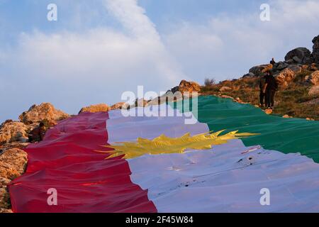 Akre, Irak. März 2021, 18th. Kurden setzen in der Altstadt von Akre eine Flagge Kurdistans über einen der Berge.die Stadt Akre im Gouvernement Duhok bereitet sich darauf vor, Nowruz (das persische Neujahr oder das kurdische Neujahr) zu feiern, indem sie Fahnen über den Bergen aufhängen. Das persische Neujahr oder das Kurdische Neujahr ist eine alte zoroastrische Tradition, die von Iranern und Kurden am 20th. März jedes Jahres gefeiert wird und mit der Frühlingstaquinoktikum zusammenfällt. (Foto: Ismael Adnan/SOPA Images/Sipa USA) Quelle: SIPA USA/Alamy Live News Stockfoto