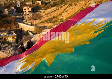 Akre, Irak. März 2021, 18th. Kurden setzen in der Altstadt von Akre eine Flagge Kurdistans über einen der Berge.die Stadt Akre im Gouvernement Duhok bereitet sich darauf vor, Nowruz (das persische Neujahr oder das kurdische Neujahr) zu feiern, indem sie Fahnen über den Bergen aufhängen. Das persische Neujahr oder das Kurdische Neujahr ist eine alte zoroastrische Tradition, die von Iranern und Kurden am 20th. März jedes Jahres gefeiert wird und mit der Frühlingstaquinoktikum zusammenfällt. (Foto: Ismael Adnan/SOPA Images/Sipa USA) Quelle: SIPA USA/Alamy Live News Stockfoto