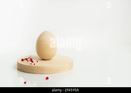 Ostern kreative minimalistische Komposition mit Holzei und Blumen auf den Holzzylinderformen. Osterkonzept. Speicherplatz kopieren. Stockfoto