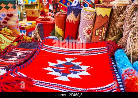 Die Teppichrollen, Teppiche und Kissenbezüge, dekoriert mit farbigen Stammesmustern im Stand von Al Souk al Kabir (Old Market) in Dubai, VAE Stockfoto