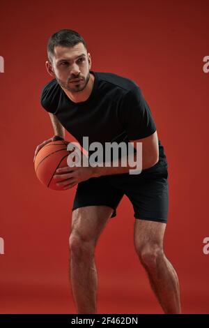 Fokussierter ernsthafter Sportler im schwarzen Sportswear Training isoliert auf Rot Hintergrund Stockfoto