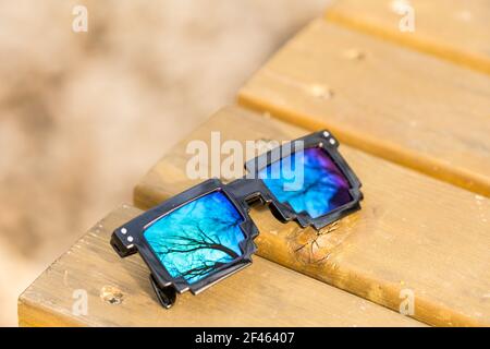 Schwarze Pixel-Sonnenbrille mit blauen Gläsern in der Nähe an einem sonnigen Tag. Selektiver Fokus Stockfoto