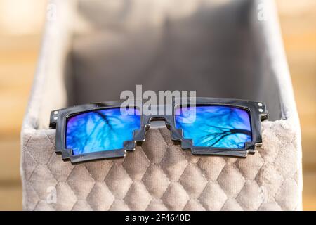 Schwarze Pixel-Sonnenbrille mit blauen Gläsern in der Nähe an einem sonnigen Tag. Selektiver Fokus Stockfoto