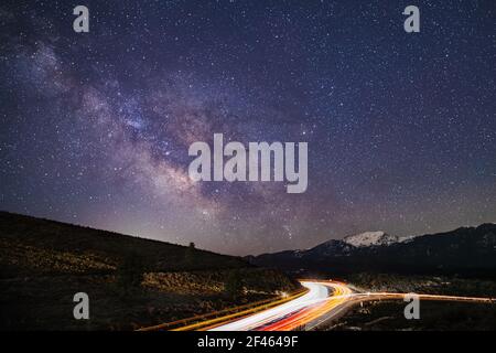 Leichte Spuren des Autobahnverkehrs Streifen in Richtung und von der Milchstraße Kern. US Highway 395 bei Bass Hill, Lassen County, Kalifornien, USA. Stockfoto