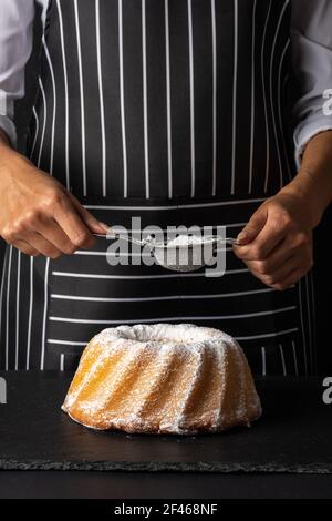 Frau Puder von Zucker zu Vanille gebundener Kuchen auf dunklem Hintergrund. Stockfoto