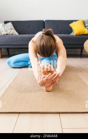 Portrait einer jungen Frau, die drinnen Yoga praktiziert. Frau praktiziert janu sirsasana zu Hause. Stockfoto