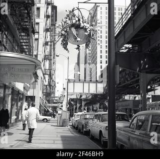 1960s, historisch, tagsüber und in der Innenstadt von Chicago, USA, Wabash Avenue, zeigt einen Abschnitt der oberirdischen oder erhöhten Eisenbahnlinie, die Chicago 'L', das S-Bahn-System, das die Stadt bedient, betrieben von der Chicago Transit Authority (CTA). Autos parkten auf der Straße, die House Tavern auf der linken Seite und das Millers Hochhaus auf der rechten Seite. Stockfoto