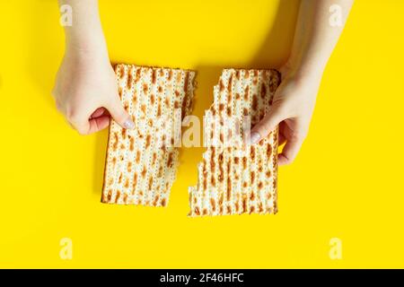 Frohe Passah. Traditionelles Brot Matzo in Händen auf gelbem Hintergrund. Jüdischer Feiertag Pesach, Platz für Text. Stockfoto
