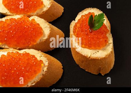 Sandwiches mit lachsrotem Kaviar auf dunklem Steingrund. Stockfoto