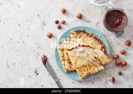 Hausgemachte Crepes, leckere dünne Pfannkuchen mit Schokolade und Nüssen. Stockfoto