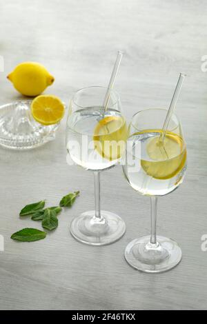 Zwei Gläser mit Wasser und frische Zitronenscheibe und ein Zitruspresse im Hintergrund Stockfoto