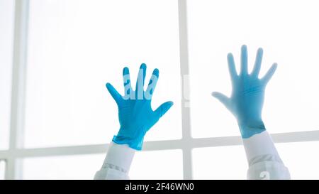 Zugeschnittenes Bild eines Chirurgen trägt Schutzhandschuhe stehen mit seinen Händen nach oben. Stockfoto