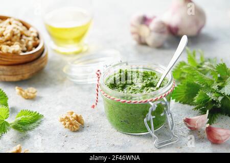 Vegetarische Brennnessel, Knoblauch und Walnusspesto. Nahaufnahme des Krug mit hausgemachtem Brennnesselpesto mit Walnüssen und Knoblauch. Stockfoto