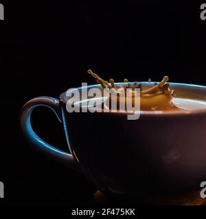 Eine schöne Aufnahme von spritzendem Kaffee in einer Kaffeetasse Auf schwarzem Hintergrund Stockfoto