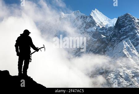 Silhouette des Menschen mit Eispickel in der Hand und in den Bergen Mit Wolken - Mount Thamserku und Mount Kangtega - Nepal Stockfoto