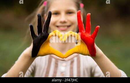 Kinder Hände in Belgien Flagge Farbe gemalt zeigen Symbol des Herzens und Liebe Geste auf Natur Hintergrund. Konzentrieren Sie sich auf die Hände Stockfoto