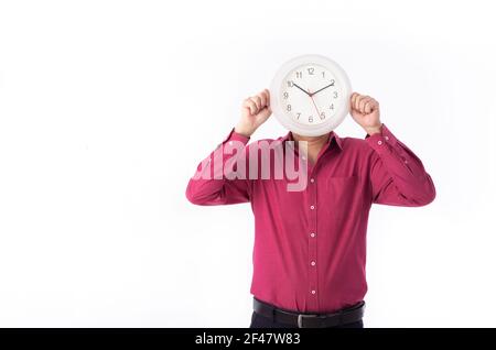 Ein Geschäftsmann hält eine Uhr direkt vor seinem Gesicht. Isoliert auf weißem Hintergrund. Stockfoto