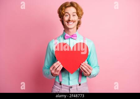 Foto von jungen glücklich positive gute Laune fröhlich funky Gentleman Halten Sie große rote Herz isoliert auf rosa Hintergrund Stockfoto