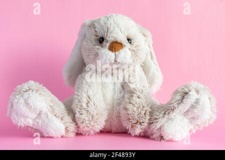 Gefüllter Hase auf rosa Hintergrund. Osterkonzept. Niedliches Spielzeug Hase sitzt auf farbigem Hintergrund. Stockfoto