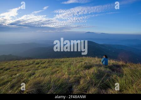 Eine Dame, die die herrliche Aussicht von einem Hügel in Wayanad am frühen Morgen genießt (Bild aufgenommen in Wayanad, Kerala) Stockfoto