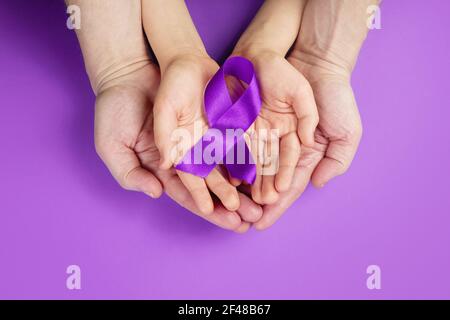 Violetter Tag. Welttag der Epilepsie. Hände mit violettem Band auf violettem Hintergrund Stockfoto