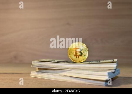 Bitcoin auf einem Bündel mit Dollarscheinen auf Holztischhintergrund. BTC-Bergbau- und Investitionskonzept. Blockchain und Finanztechnologie. Kryptopreise Stockfoto