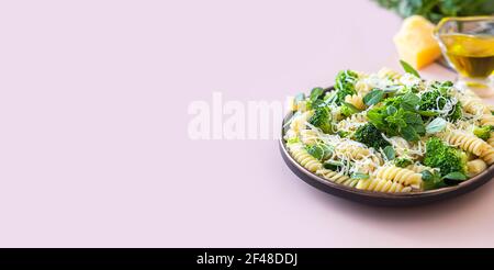 Fusilli mit Brokkoli, Basilikum und Parmesan auf beigem Hintergrund. Richtige Ernährung. Sporternährung. Diätmenü. Selektiver Fokus Stockfoto