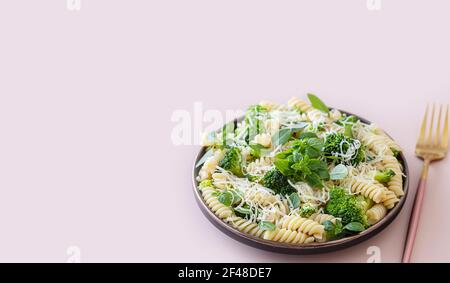 Fusilli mit Brokkoli, Basilikum und Parmesan auf beigem Hintergrund. Richtige Ernährung. Sporternährung. Diätmenü. Selektiver Fokus Stockfoto