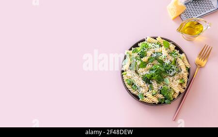 Fusilli mit Brokkoli, Basilikum und Parmesan auf beigem Hintergrund. Richtige Ernährung. Sporternährung. Diätmenü. Selektiver Fokus Stockfoto
