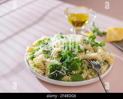 Fusilli mit Brokkoli, Basilikum und Parmesan auf beigem Hintergrund. Richtige Ernährung. Sporternährung. Diätmenü. Stockfoto