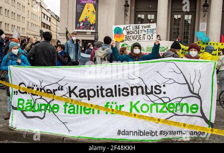 Demonstrantinnen halten transparent: ' Grüner Kapitalismus: Bäume fällen für Konzerte ' und Demonstrantin hält Schild: ' Handeln Sie, wie Ihr Haus brennt! Weil es so ist! ' Am 19. März 2021 sammeln sich in München Hunderte, um für die Inhalation des Pariser Klimakommits und das 1, 5 Grad Ziel zu demontieren. Sie zogen vom Wetterstenplatz zum Gärtnerplatz. * am 19 2021. März versammelten sich Hunderte in München, Deutschland, um für das Pariser Klimaabkommen und das 1,5-Grad-Ziel zu protestieren. (Foto: Alexander Pohl/Sipa USA) Quelle: SIPA USA/Alamy Live News Stockfoto