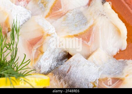 Hering und Dill in Scheiben auf dem Teller. Teil der Fischplatte Nahaufnahme. Makro. Foto kann als ganzer Hintergrund verwendet werden. Stockfoto