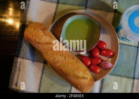 Zutaten für katalanische Tomatenbrot, pa amb tomàquet, auf einem Teller - Mini-plumb Tomaten, Baguette, Knoblauch, Meersalz und Olivenöl in einer flachen Schale. Stockfoto